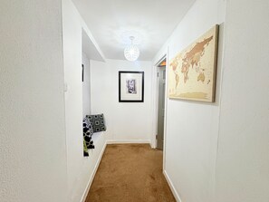Um corredor com piso coberto por carpete, um quadro na parede e uma obra de arte representando um globo.