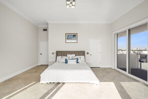 Une chambre à coucher avec un lit, une porte, une fenêtre et une vue sur la ville.