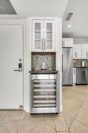 Et køkken med indbygget køleskab, hvide skabe og et flisebeklædt backsplash.