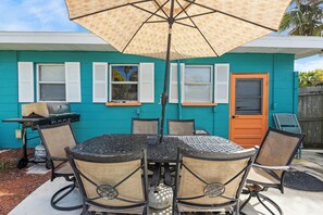 Une terrasse avec une table et des chaises, un barbecue et une porte.