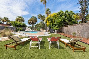 A backyard with a swimming pool, palm trees, and a wooden fence. - Beachside Retreat-Steps To Ocean-Private Heated Pool Oasis-Pet Friendly (Daytona Beach)