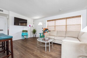 A living room with a sofa, a coffee table, and a television mounted on the wall. - Beachside Retreat-Steps To Ocean-Private Heated Pool Oasis-Pet Friendly (Daytona Beach)
