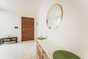 A hallway with a wooden door, a console table with a vase, and a wall-mounted mirror. - Spacious 4BR 4 Bath in Piet Up to 8 Guests (Pieta)