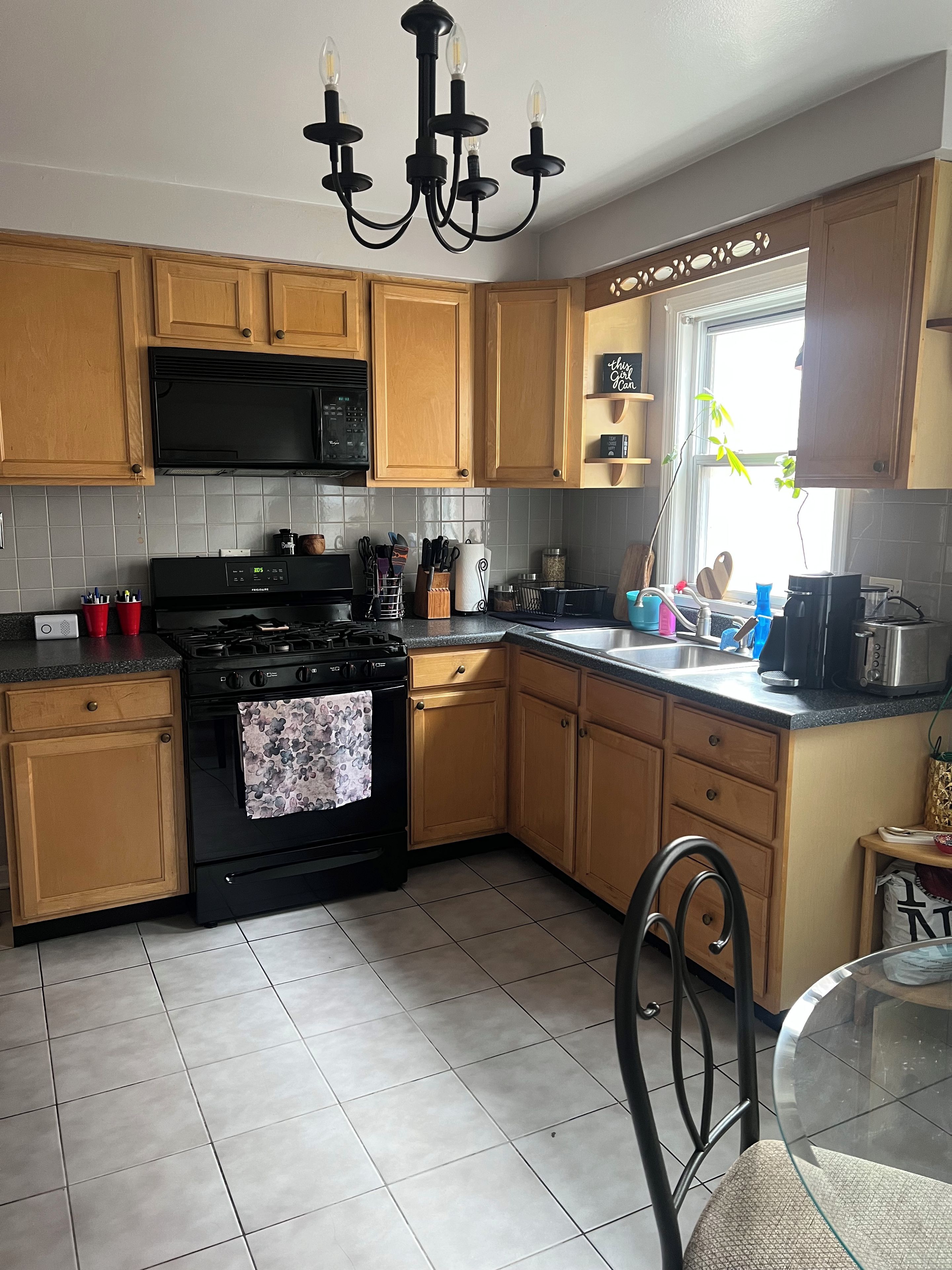 A kitchen with wooden cabinets, a black stove, a microwave, and a chandelier.