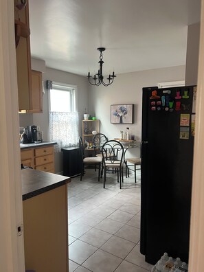 A kitchen with a dining area, a chandelier, and a refrigerator with magnets. - Cozy 2-bedroom condo with AC in gorgeous Chicago neighborhood (Chicago)