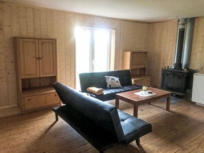A room with a sofa, a coffee table, a fireplace, and wooden walls. - in Arvidsjaur mit Terrasse by Interhome (Arvidsjaur)