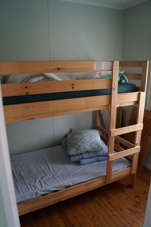 A bunk bed with a wooden frame, a lower bunk with a grey mattress, and a top bunk with a green blanket.