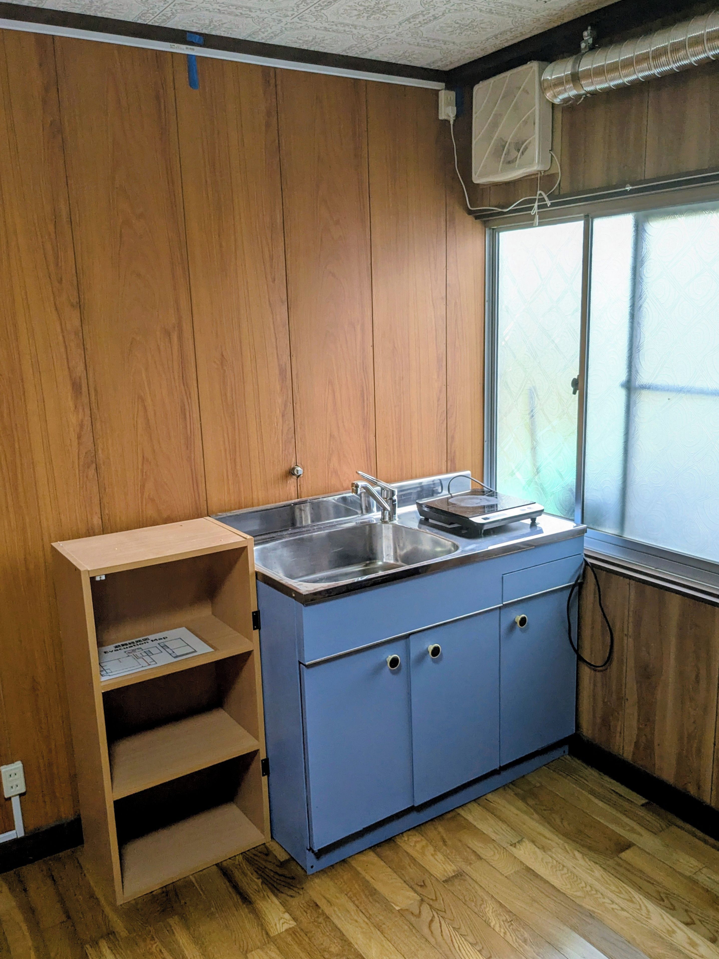 Una cucina con mobili in legno, un lavandino e una finestra con persiane.