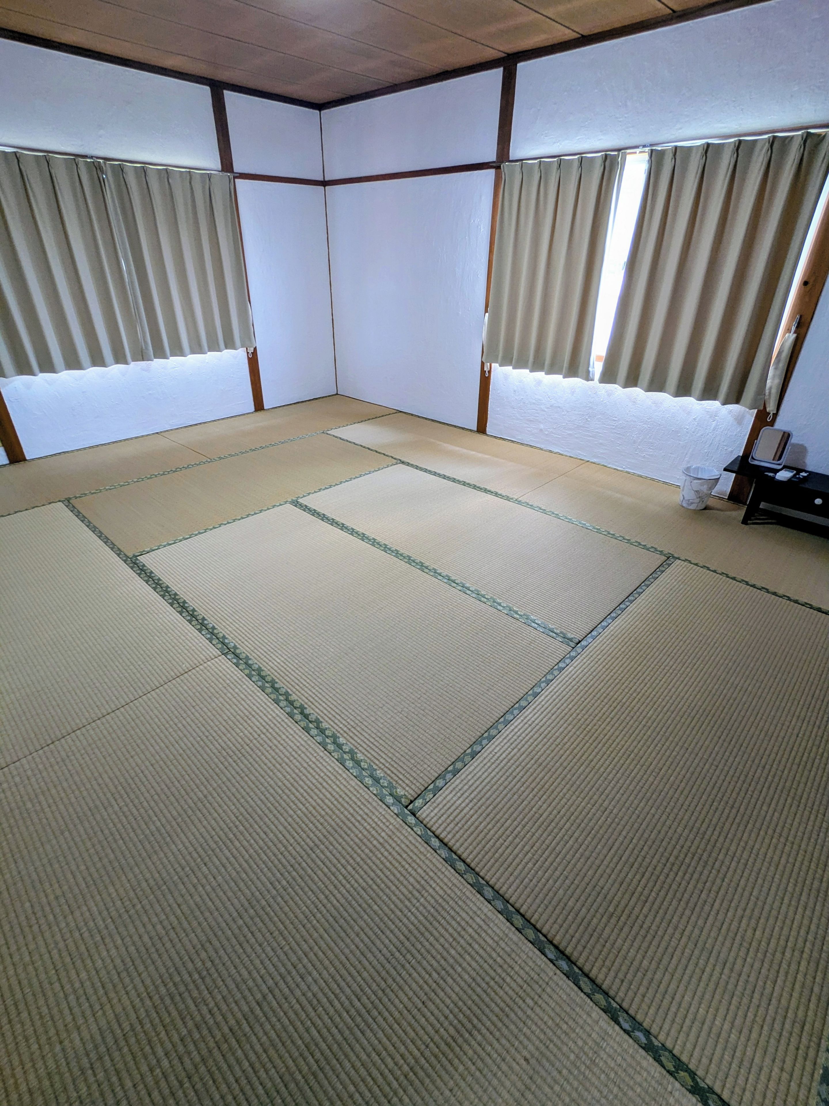 Una habitación con esteras de tatami, puertas correderas y una pequeña mesa con un espejo.