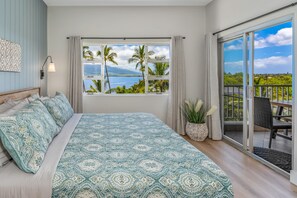 Ein Schlafzimmer mit einem großen Bett, Meerblick, einem Balkon mit einem Sessel und einem Blumentopf.