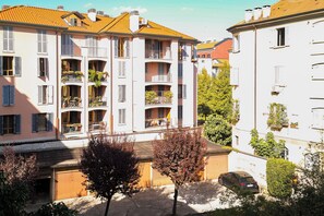 Edifício residencial com vários andares, varandas, um portão de madeira e um carro estacionado.
