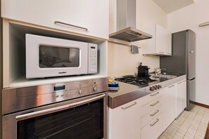Una cocina moderna con microondas integrado, horno y estufa a gas.