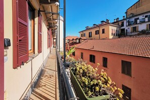 Un balcón con vistas a edificios de tejados de teja y una planta en maceta.