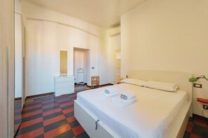 Una habitación de hotel con una cama, un escritorio, una silla y un espejo.