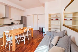 Eine moderne Küche mit weißen Schränken, einem Edelstahlkühlschrank und einem Essbereich mit Holztisch und weißen Stühlen.