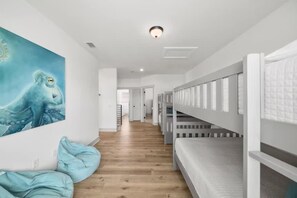 A corridor with bunk beds, a painting of an octopus, and a wooden floor. - Downtime Panama Palms | Pool, Beach, Pet-Friendly (Panama City Beach)