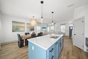 A modern kitchen with a central island, dining area with chairs, and pendant lighting. - Downtime Panama Palms | Pool, Beach, Pet-Friendly (Panama City Beach)