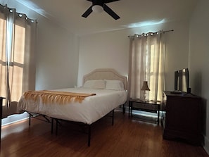 A bedroom with a bed, a nightstand, a lamp, a TV, and a ceiling fan. - 2-bedroom Bainbridge Bungalow near Historic Downtown with yard - Room for boats! (Bainbridge)