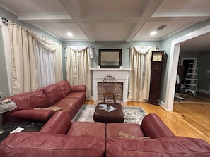 A living room with a red sofa set, a fireplace, and a clock on the wall. - 2-bedroom Bainbridge Bungalow near Historic Downtown with yard - Room for boats! (Bainbridge)