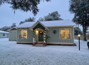 A house with a front porch, a clock on the wall, and a snow-covered yard. - 2-bedroom Bainbridge Bungalow near Historic Downtown with yard - Room for boats! (Bainbridge)