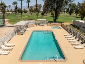 A rectangular swimming pool with a diving board, surrounded by lounge chairs and a covered seating area. - Inverness on the Green | Golf Course Views | Modern 2BR | Pool & Tennis | Palm Desert (Palm Desert)