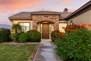 A residential house with a stone facade, a front door, and a pathway leading to the entrance. - Lago Vista Retreat | Pool & Game Room | Half Court Basketball | 4BR (Indio)