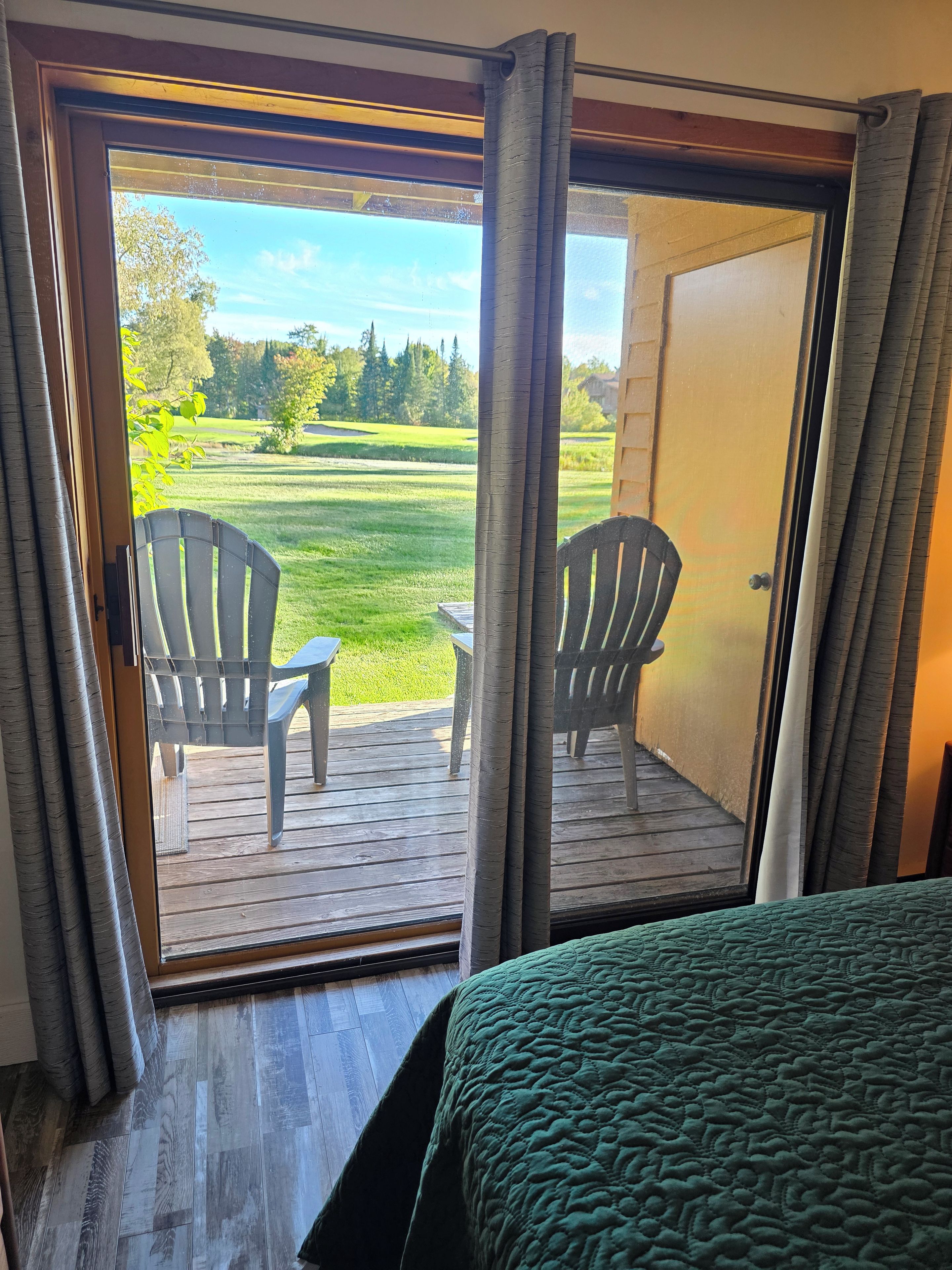 Ein Zimmer mit Blick auf eine Rasenfläche und zwei Stühle vor einer Schiebetür.