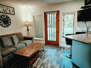 A living room with a sofa, coffee table, and a clock on the wall. - NEW rental Shanty Creek Resorts 1 bedroom on the Schuss course walk to slopes (Mancelona)