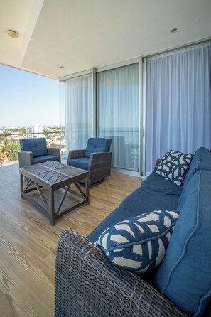A balcony with wicker furniture, a wooden table, and a sofa with patterned cushions. - Mazatlán Luxury Beach Residence - 606TN - Camino al Mar (Mazatlán)