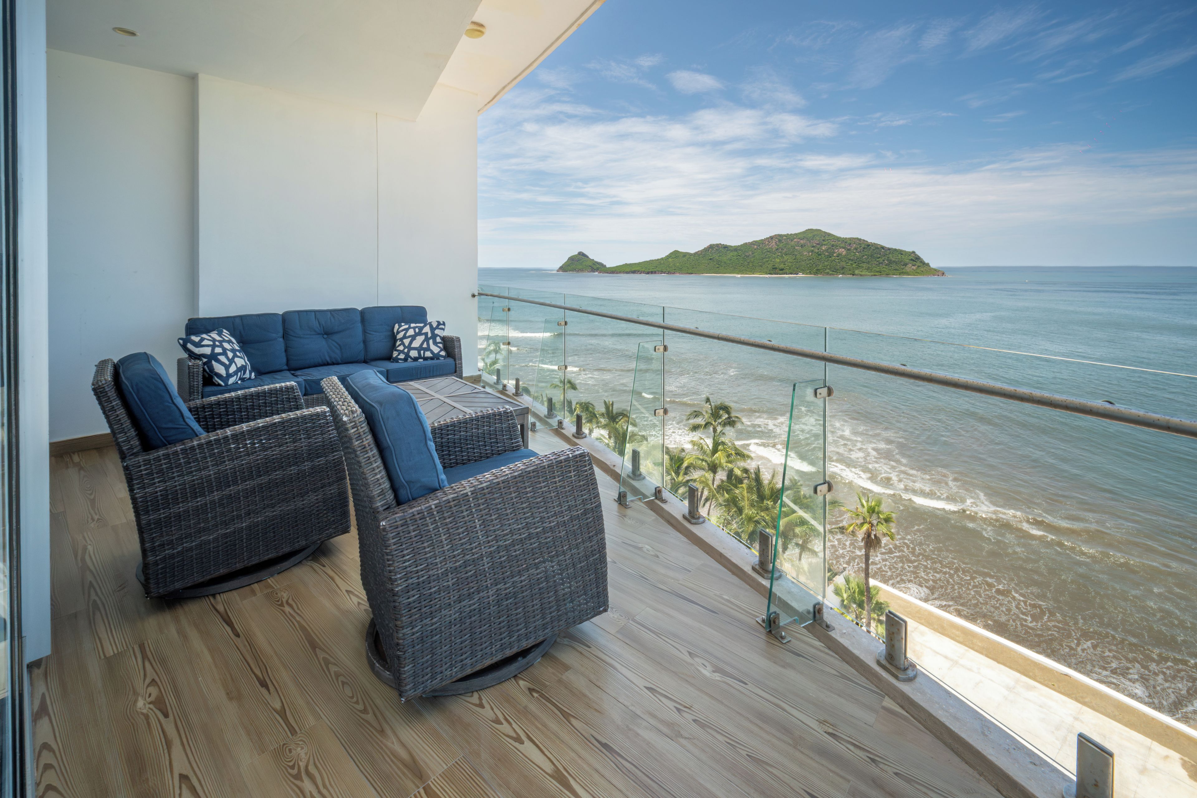A balcony with wicker furniture and a view of the sea.
