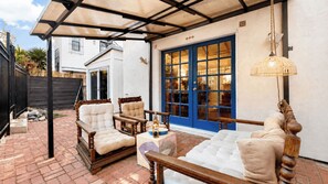 A covered patio with outdoor furniture, a blue door, and a hanging light fixture. - Windansea Bungalow by Avantstay Beach Cottage + Garden Patio Walk to Beach + Mins to La Jolla (La Jolla)