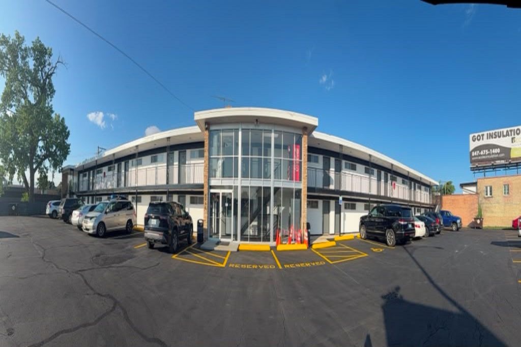A building with a curved facade, a glass entrance, and a parking lot with marked reserved spaces.