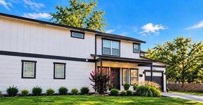A modern two-story house with a flat roof, a front porch, and a well-maintained lawn. - Modern 2BR Midterm Stay | Garage + 2 Baths (Oklahoma City)