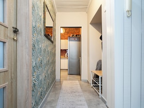 Ein Flur mit Wandverkleidung, einem Kühlschrank und einer Bank.