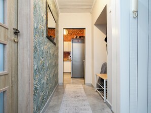 A hallway with a patterned wall, a refrigerator, and a bench. - Łódź 1 Maja Central Room #2 (Łódź)