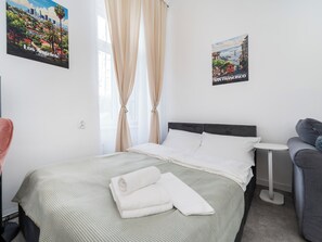 Une chambre d’hôtel avec un lit, une petite table de chevet, une chaise et deux affiches accrochées au mur.