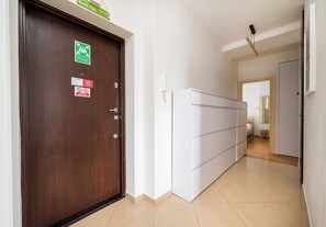 A hotel corridor with a wooden door, a white wardrobe, and a tiled floor. - Nowolipki Cozy Soul Apartment (Warszawa)