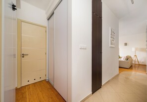 Un pasillo con una puerta color beige, una puerta de madera oscura y una pared blanca con un cuadro enmarcado.