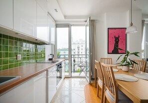 Una cocina moderna con un salpicadero de azulejos verdes, encimera de madera y un comedor con mesa y sillas.