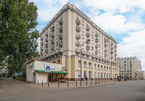 A multi-story building with balconies, a ground-level entrance, and a visible storefront. - Nowolipki Cozy Soul Apartment (Warszawa)