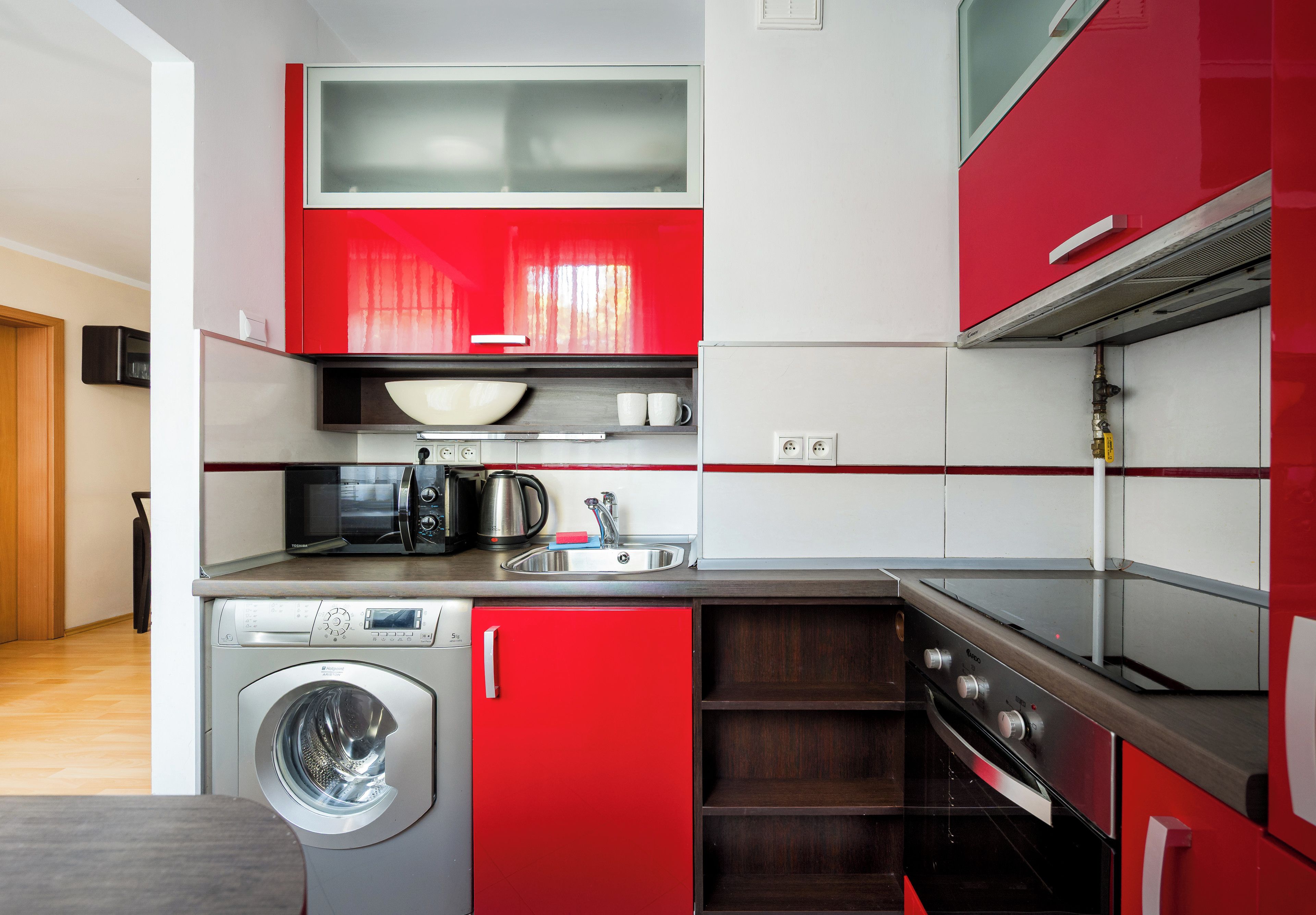 Een kleine keuken met een wasmachine, magnetron en een fornuis.