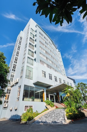 Un hotel moderno con una estructura de varios pisos, amplias ventanas y una zona de acceso cubierta.