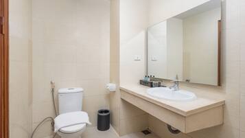 Een badkamer met toilet, wastafel, spiegel en prullenbak.