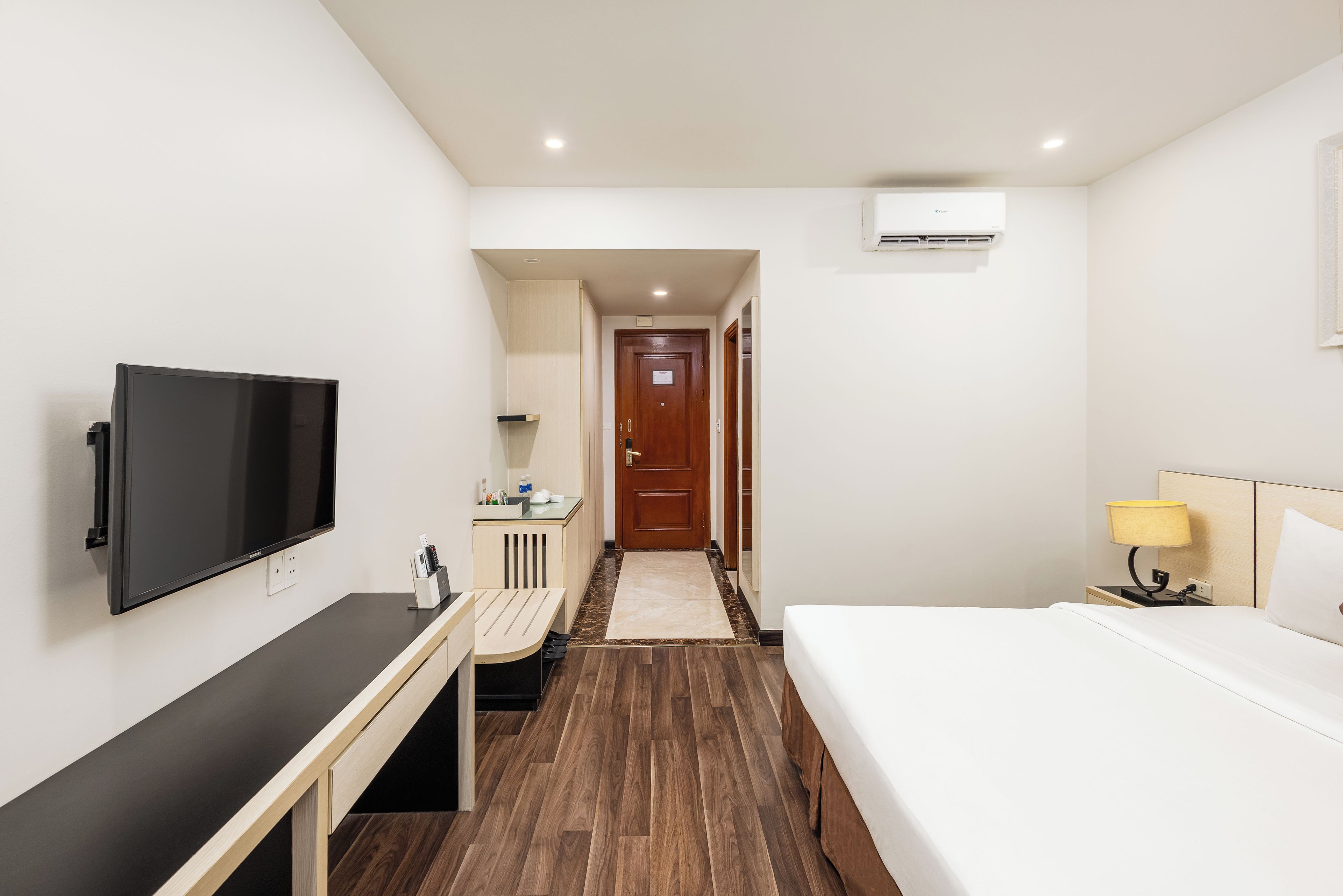 Une chambre d’hôtel comprenant un lit, un bureau avec un téléviseur à écran plat, une table de chevet, une lampe et une armoire.