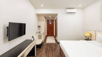 Une chambre d’hôtel comprenant un lit, un bureau avec un téléviseur à écran plat, une table de chevet, une lampe et une armoire.