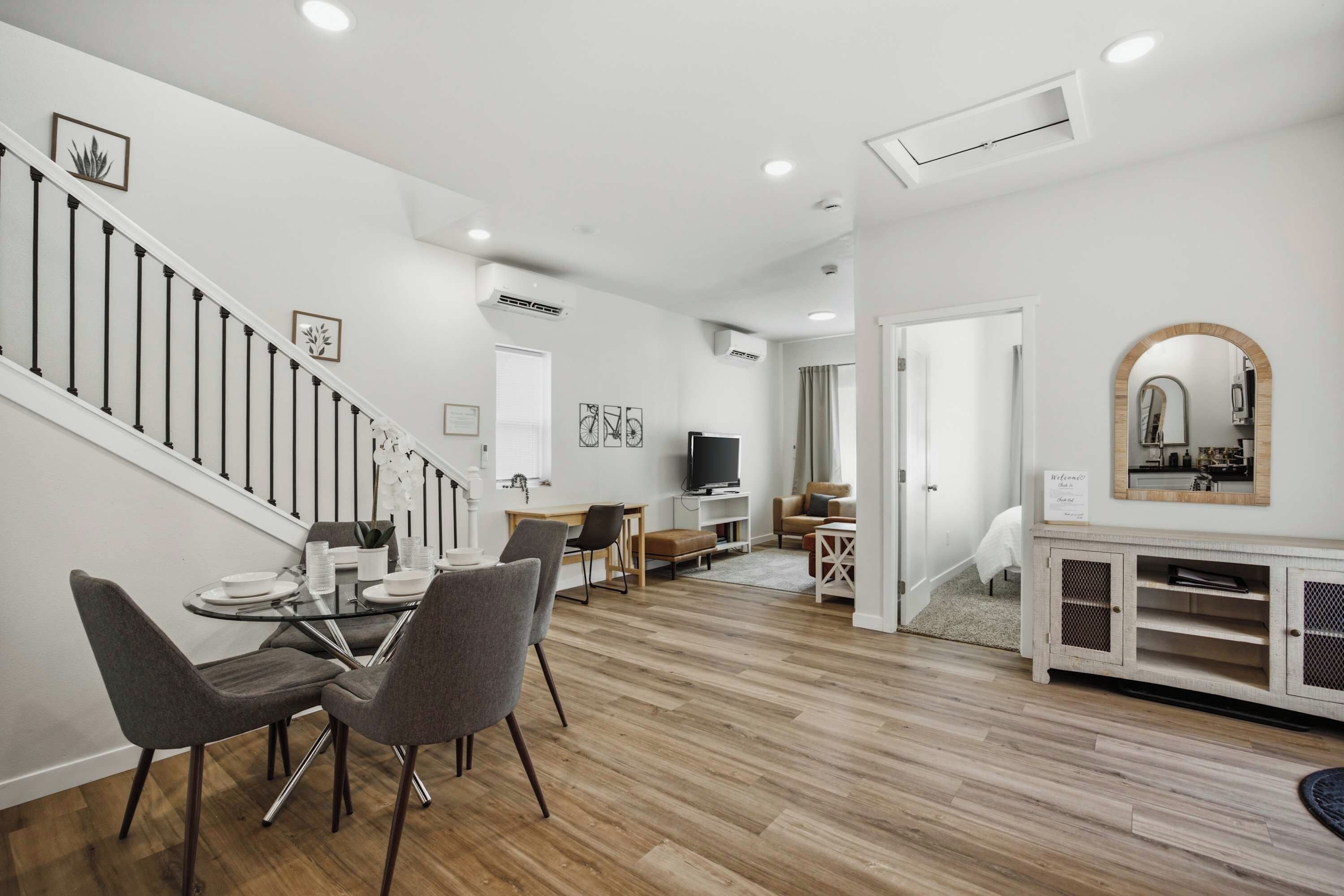A modern living space with a staircase, dining area, and a kitchen.