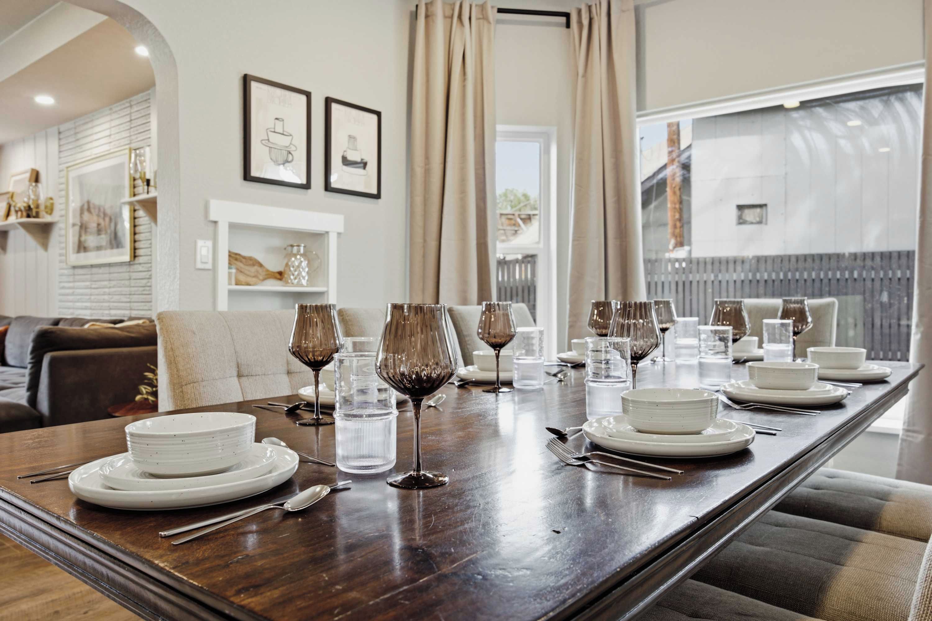 A dining table set for a meal with white plates, clear glasses, and wine glasses.