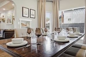 A dining table set for a meal with white plates, clear glasses, and wine glasses. - The Evergreen Home | King Beds + Fire Pit (Loveland)