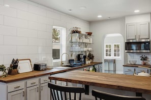 A modern kitchen with white cabinetry, a wooden countertop, and a built-in oven. - The Evergreen Home | King Beds + Fire Pit (Loveland)