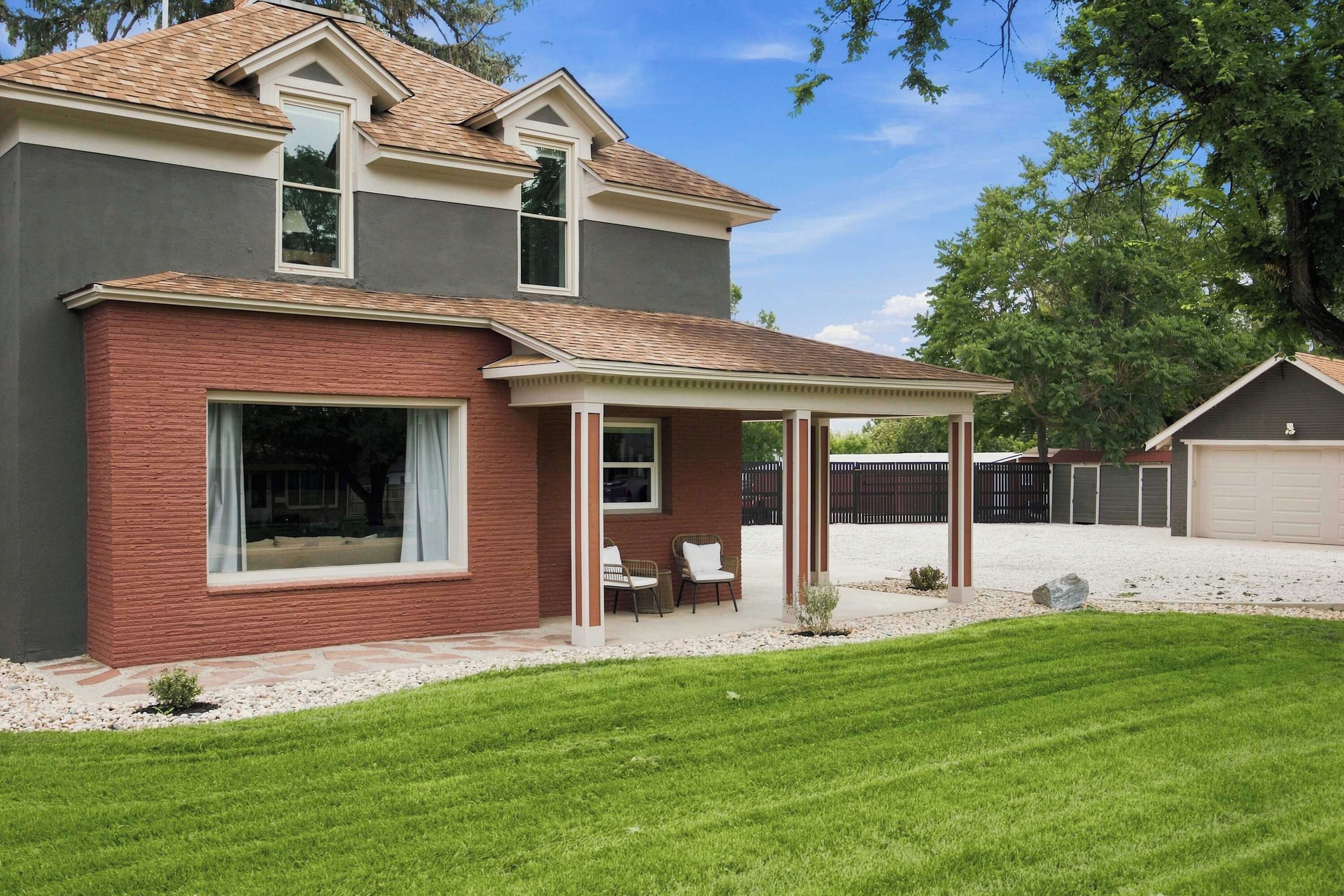 A two-story house with a covered patio, a garage, and a well-maintained lawn.